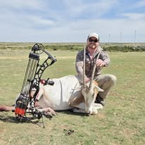 Hunter displaying the scimitar oryx he shot with his bow.